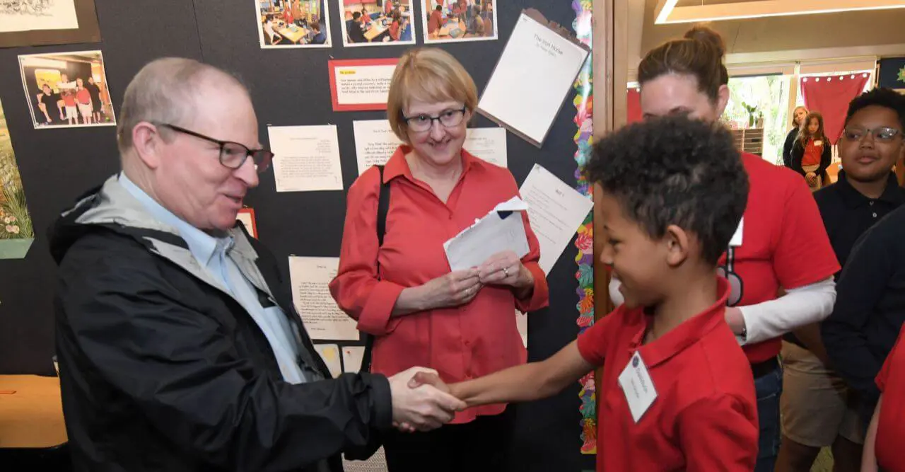 ULS Alumni shakes hands with a current student.