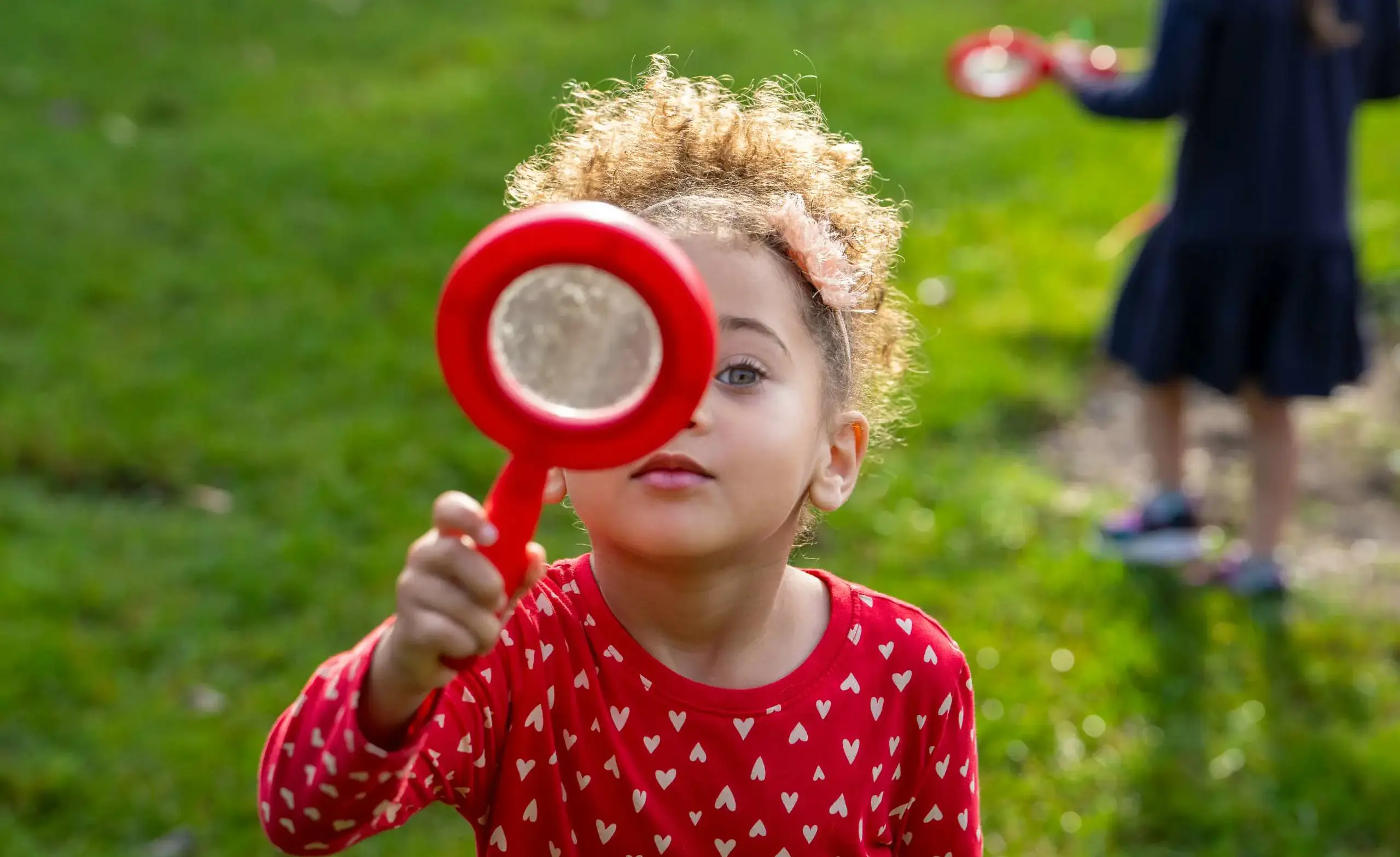Preschool age child looking through magnifying glass.