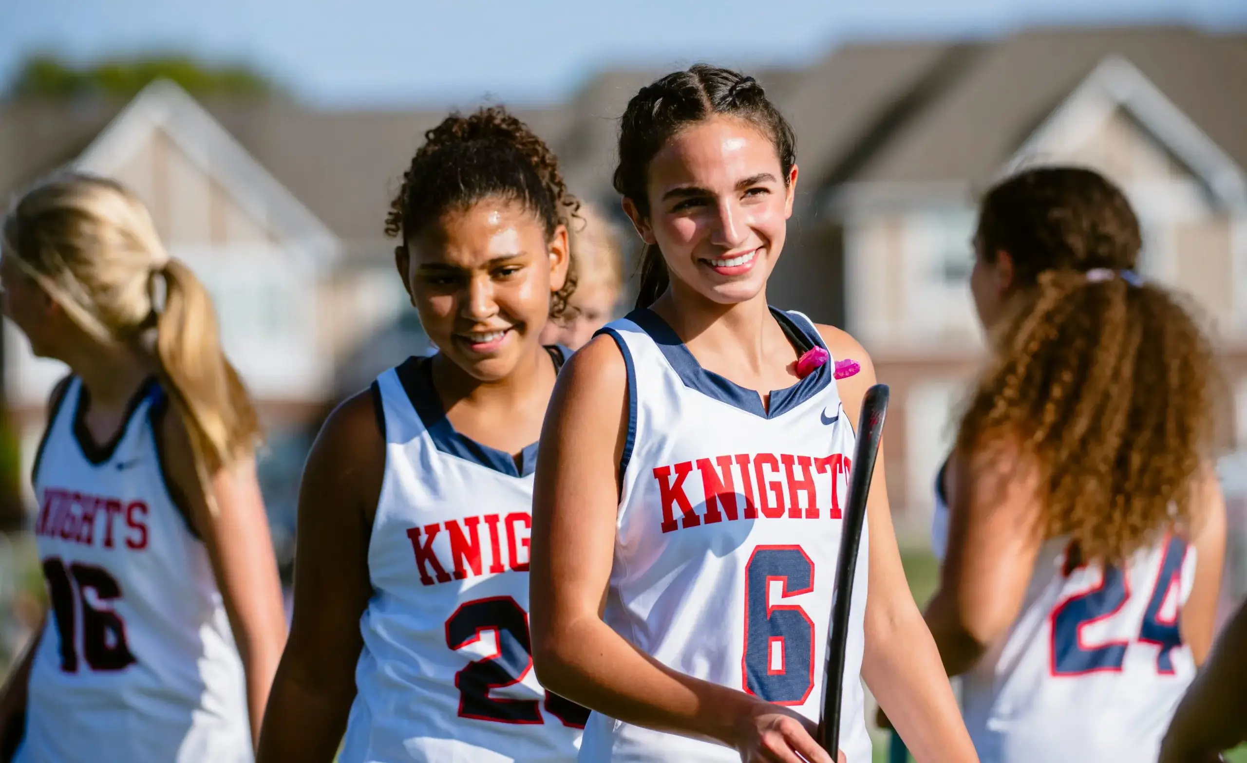 Girls field hockey team members smile