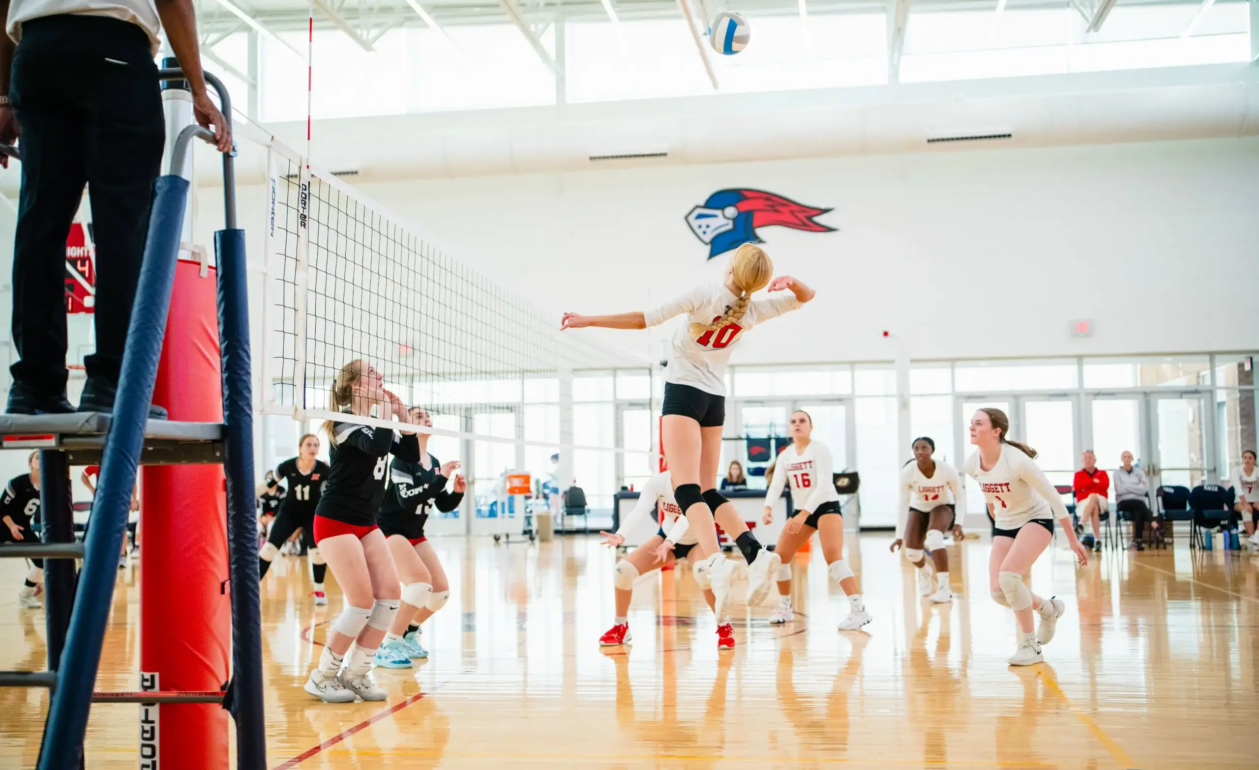 Volleyball player spikes ball at the net during volleyball game.