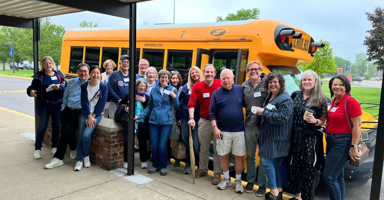 Alumni standing near school bus