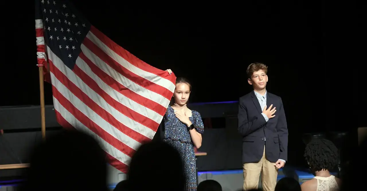 two children on stage with American flag