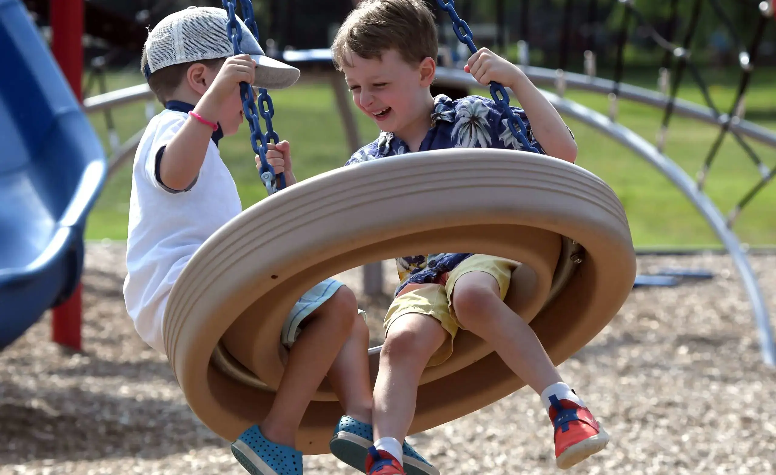 Boys swing on tire swing at summer day camp