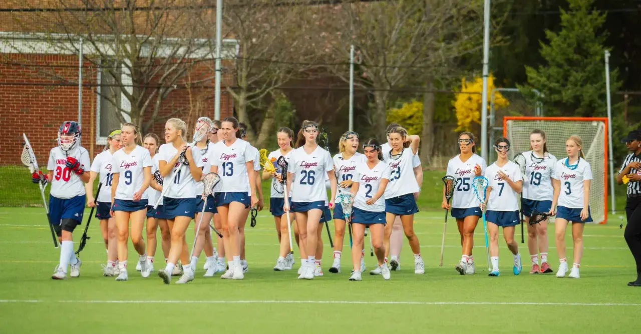 Upper School Girl's Lacrosse Team walking across a sports field.